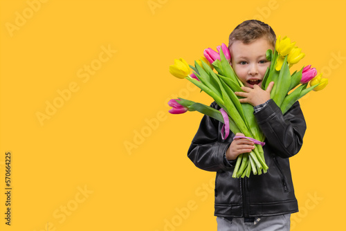 Portrait of smiling cute boy with yellow and pink bouquet tulips for Mammy. Spring flowers concept Mother's Day Gift for Woman