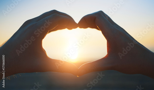 Hands of man and woman made heart shape at sunset.