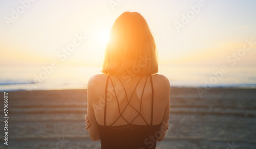 Teenage girl by the sea at sunset.