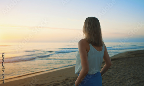 Woman stands on deserted beach and looks into the distance.