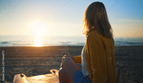 Foto Woman sits on a boat and looks at the sea at sunset.