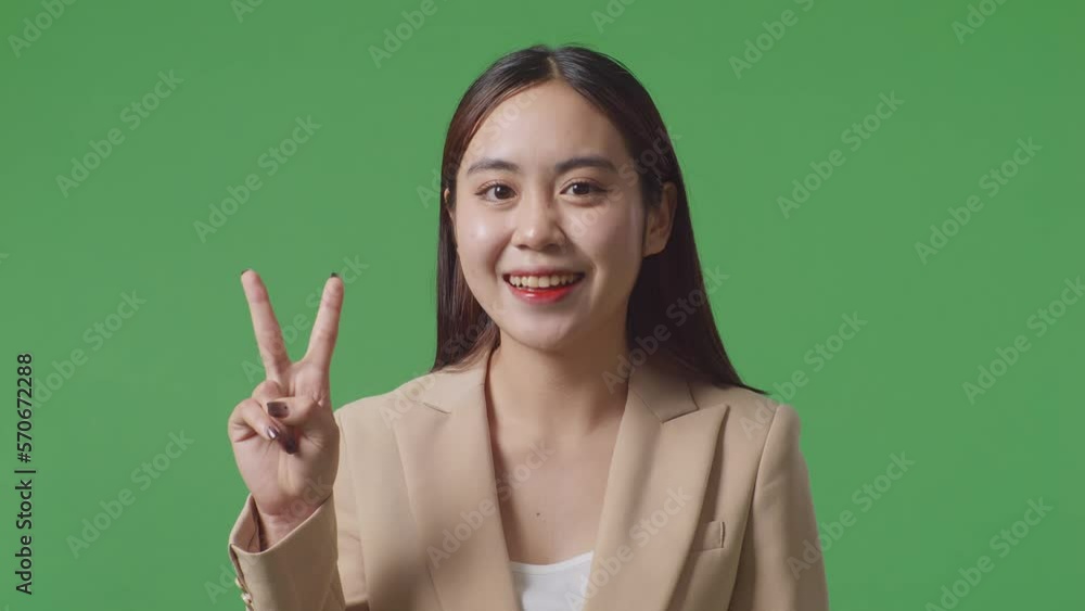 Close Up Of Asian Business Woman Showing Gesture Peace And Smiling While Standing On Green Screen In The Studio
Close Up Of Asian Business Woman Showing Gesture Peace And Smiling While Standing On Green Screen In The Studio