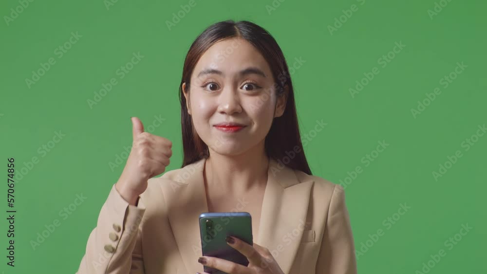Close Up Of Asian Business Woman Using Smartphone And Showing Thumb Up While Standing On Green Screen In The Studio
Close Up Of Asian Business Woman Using Smartphone And Showing Thumb Up While Standing On Green Screen In The Studio