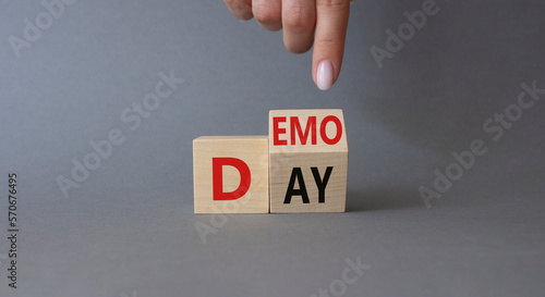 Demo Day symbol. Businessman hand points at turned wooden cubes with concept words Demo Day. Beautiful grey background. Business and Demo day concept. Copy space