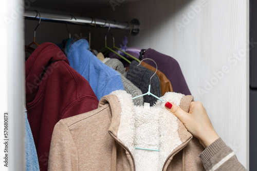 woman takes warm clothes out of the closet