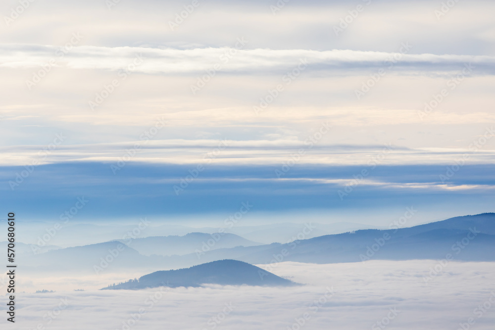 Beautiful foggy winter scenery with clouds and mountain peaks