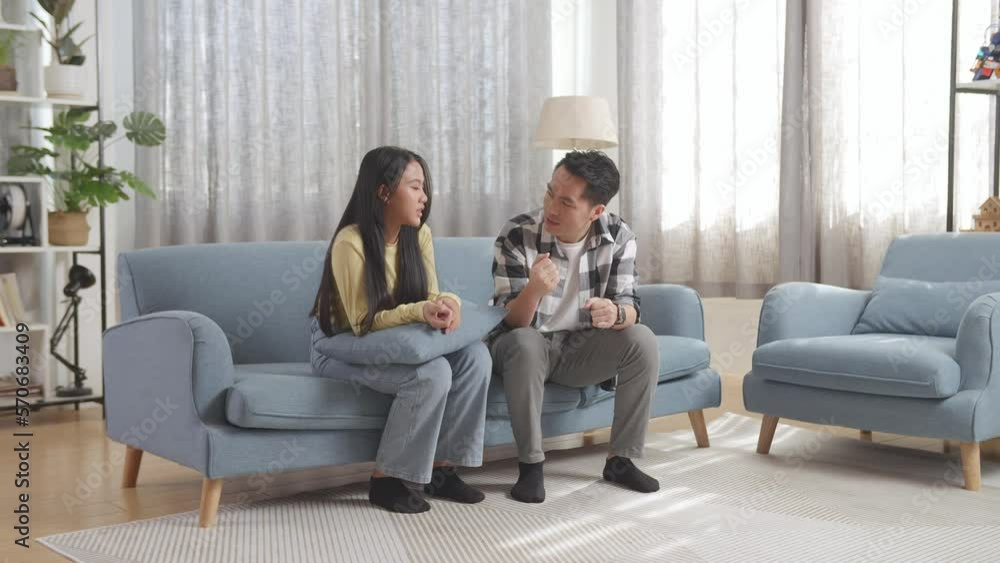 Asian Father Explaining Something To His Daughter Then Raising Hand And Showing Thumbs Up Gesture To Encourage Her On A Sofa In The Living Room
Asian Father Explaining Something To His Daughter Then Raising Hand And Showing Thumbs Up Gesture To Encourage Her On A Sofa In The Living Room