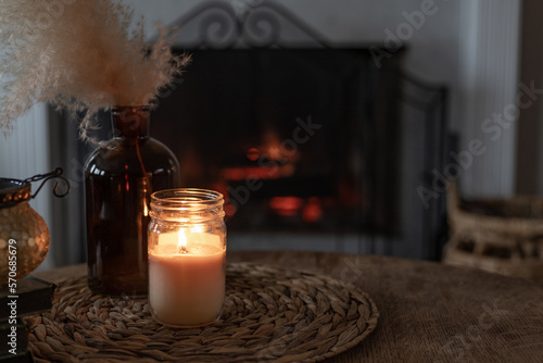candle mock-up on wooden table and pampas grass with fireplace in background