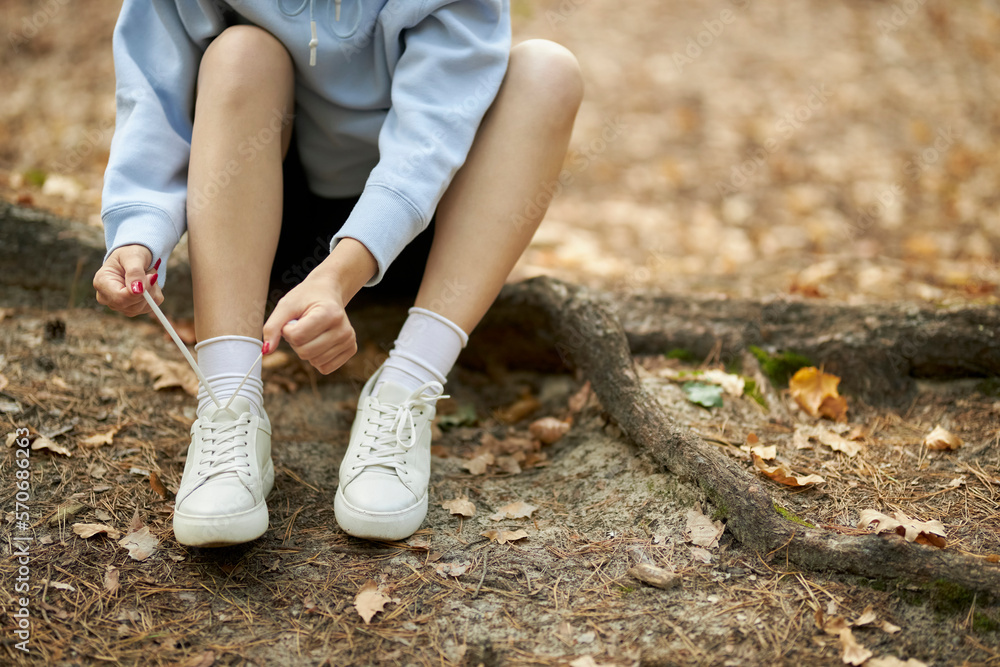 young athlete. beautiful girl athlete tying shoelaces on sneakers in the park. beautiful athlete girl sits tying shoelaces on white sneakers. The concept of a healthy lifestyle.