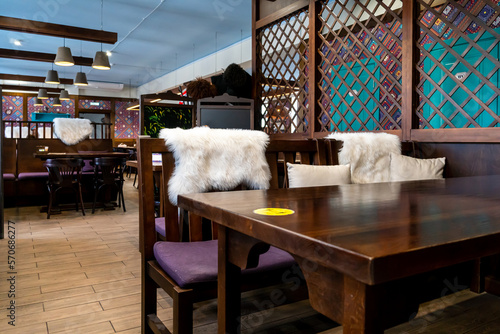 Interior design in a Georgian restaurant. Wooden furniture for cafes. Cozy wooden chairs. Pillows and blankets in a trendy restaurant for guests.