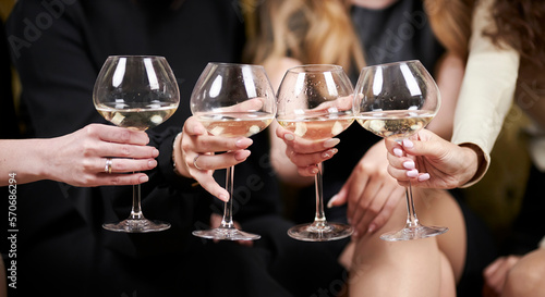 girls at the party hold four glasses of champagne in their hands, close-up. stylish young ladies hold clinking glasses with toasts. Close-up of women's hands clinking champagne glasses.