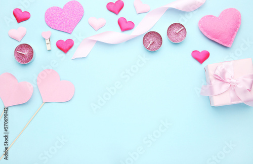 Hearts with gift box, ribbon and candles on blue background