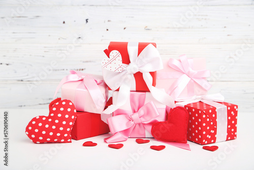 Gifts boxes and hearts on white wooden background