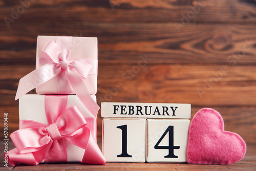 Gift boxes with fabric heart and cube calendar on brown wooden background