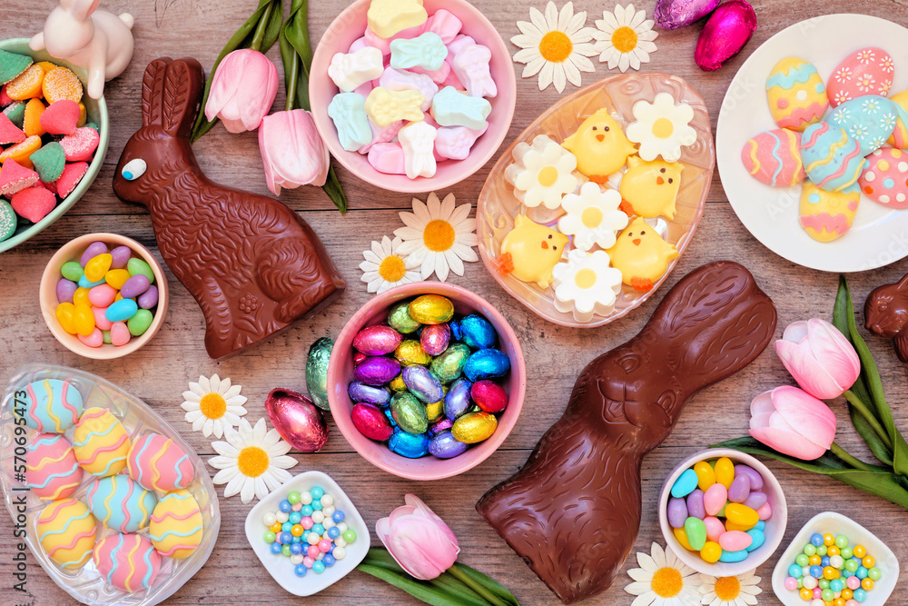Easter candies. Top view table scene over a wood background. Chocolate bunnies, candy eggs and a variety of sweets.