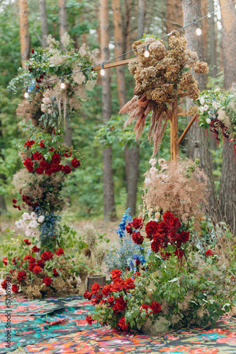 A beautiful arch with intertwined fresh flowers at a wedding ceremony in a green park. arch with flowers