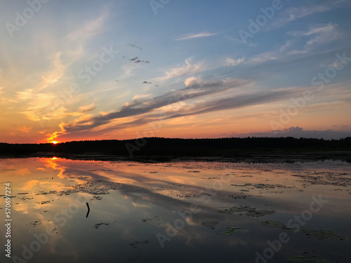 Sunset on a lake with blue skies and clouds reflecting in the water. Tourism and travel concept.