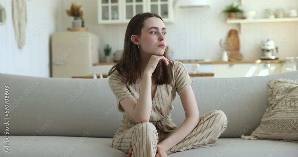 Beautiful young 20s woman reflecting seated on sofa, feels bored on weekend alone at home, looks thoughtful deep in sad thoughts, waiting or missing for boyfriend, suffers from loneliness, recollects Beautiful young 20s woman reflecting seated on sofa, feels bored on weekend alone at home, looks thoughtful deep in sad thoughts, waiting or missing for boyfriend, suffers from loneliness, recollects