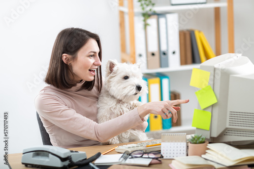 A beautiful girl and a white dog work at a retro computer.