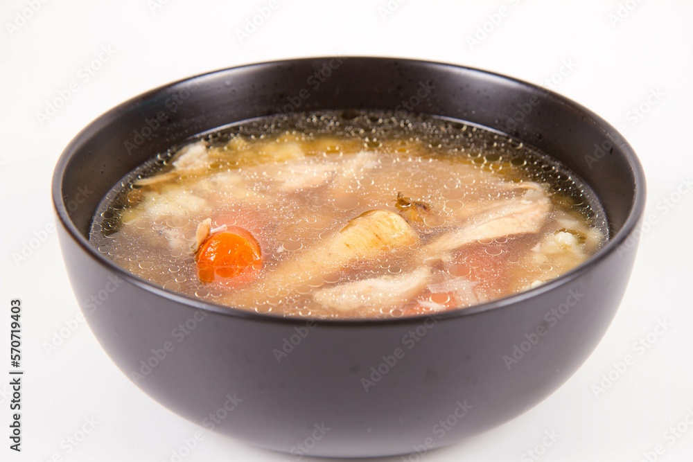 Chicken soup with noodle and carrot and parsley roots, chicken meat visible, in a bowl on a white background Chicken soup with noodle and carrot and parsley roots, chicken meat visible, in a bowl on a white background