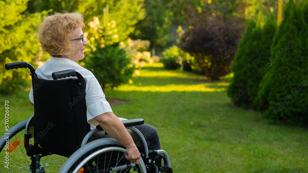 Happy elderly woman sitting in a wheelchair on a walk outdoors. Happy elderly woman sitting in a wheelchair on a walk outdoors.