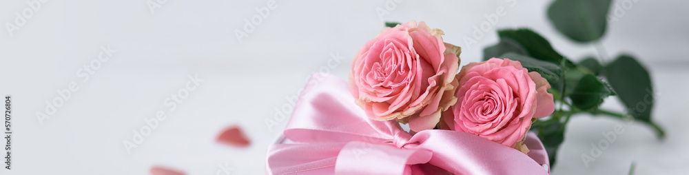 Beautiful surprise greeting for saint Valentine's or Women's Day, birthday or Anniversary for beloved. Fresh pink roses, gift box with sweets. White background. Holiday atmosphere. Banner copy space Beautiful surprise greeting for saint Valentine's or Women's Day, birthday or Anniversary for beloved. Fresh pink roses, gift box with sweets. White background. Holiday atmosphere. Banner copy space