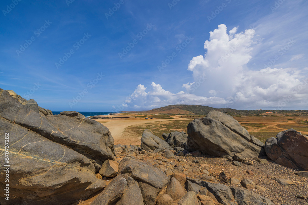 Close-up view of large rocks in desert on Caribbean coast against blue sky with white clouds Aruba island.