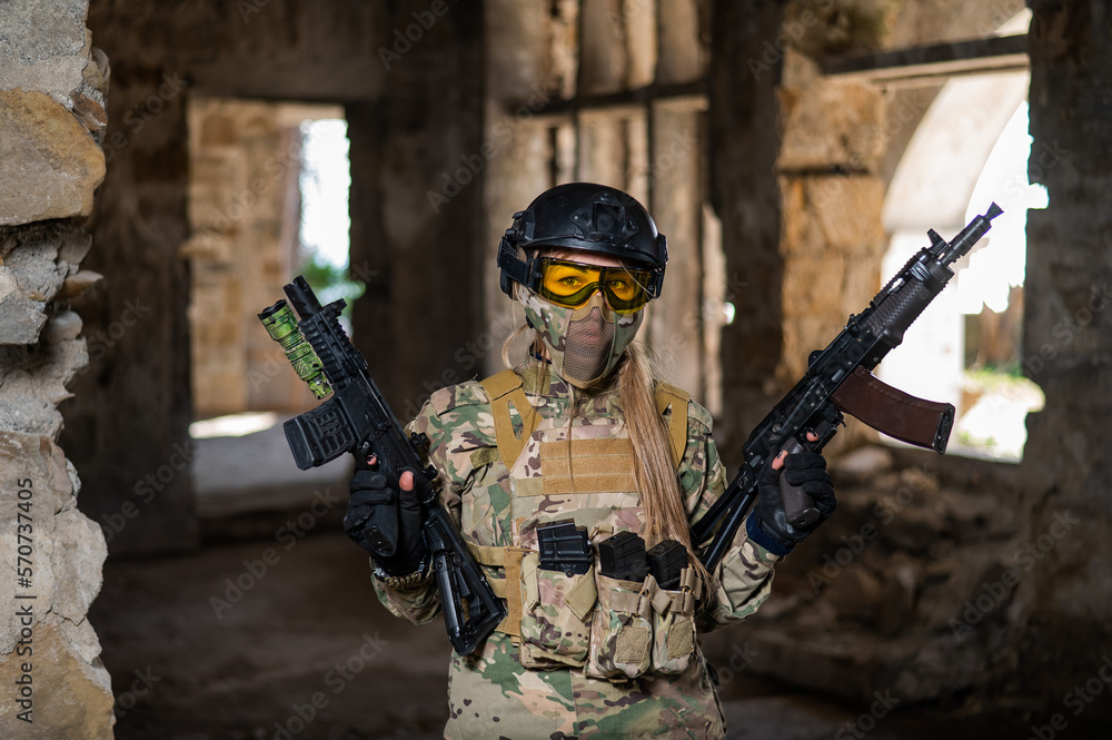 Fototapeta premium A woman in an army uniform holds a firearm in an abandoned building.