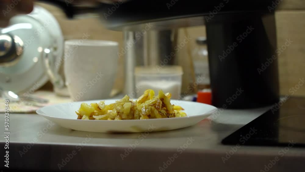 Apply fried potatoes from the pan to the plate, in the kitchen. Apply fried potatoes from the pan to the plate, in the kitchen.