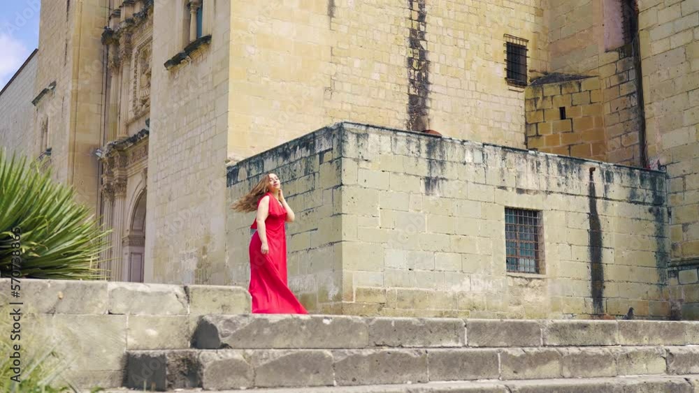Slow motion of woman walking near Church of Santo Domingo de Guzmán, happy Hispanic female in red dress looking while strolling on sunny day in center of Oaxaca, Mexico Slow motion of woman walking near Church of Santo Domingo de Guzmán, happy Hispanic female in red dress looking while strolling on sunny day in center of Oaxaca, Mexico