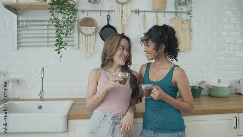 Holiday concept of 4k Resolution. Asian women having coffee together in the kitchen. Young women are in a mutual lesbian love relationship.