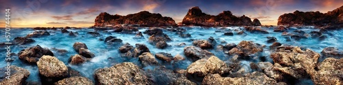 Rocky ocean shore featuring waves crashing against solid craggy stones breaching the ocean surface