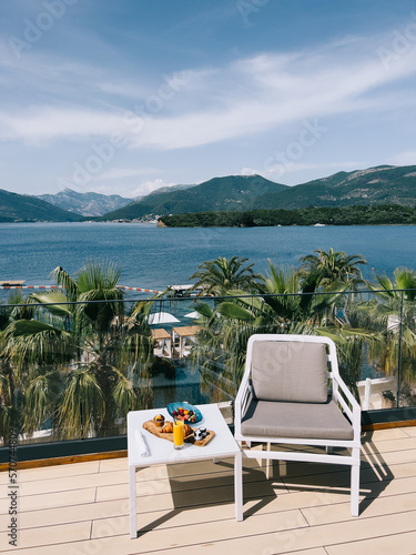 Continental breakfast on a table near an armchair on a hotel terrace by the sea