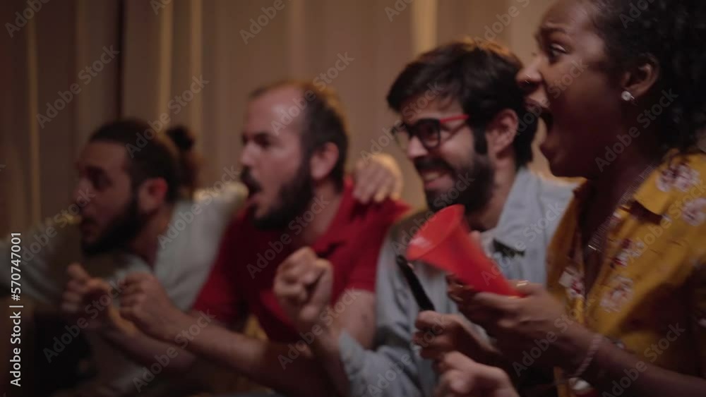 Fans of a soccer team follow the game at home, celebrating the winning goal in the World Cup match. Enthusiastic people enjoying the sporting success watching on TV. Fans of a soccer team follow the game at home, celebrating the winning goal in the World Cup match. Enthusiastic people enjoying the sporting success watching on TV.