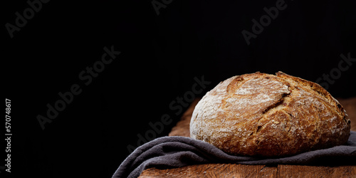 Wheat artisan sourdough bread on a wooden table black background. Panoramic view, free space for text