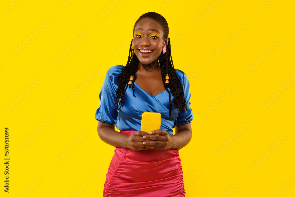 Happy Black Female Using Phone Standing On Yellow Studio Background Happy Black Female Using Phone Standing On Yellow Studio Background