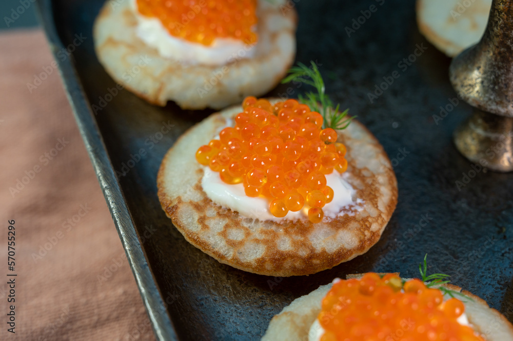 Tasty appetizer for dinner, small pancakes bliny with red fish caviar and sour cream Tasty appetizer for dinner, small pancakes bliny with red fish caviar and sour cream