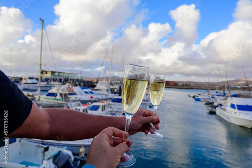 Everyday party, hands with glasses of cava or champagne sparkling wine in yacht harbour of Caleta Fuste, Fuerteventura, Canary islands vacation, Spain photo