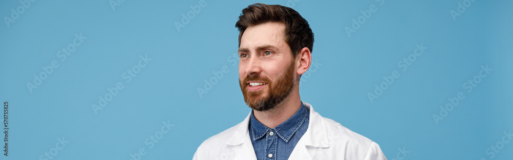 Fototapeta premium Portrait of handsome professional doctor looking away standing over blue studio background