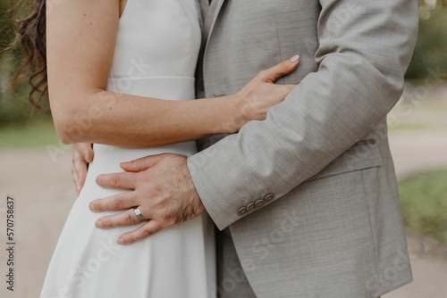 Salon du mariage d'un un couple qui s'enlace avec une mariée en robe blanche et marié en costume gris