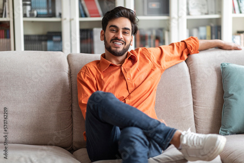 Cool middle eastern guy chilling at home, smiling at camera © Prostock-studio