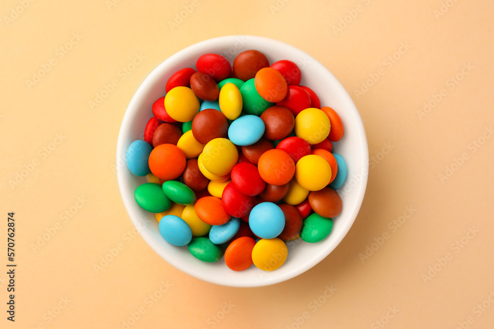 Bowl with tasty colorful candies on beige background, top view Bowl with tasty colorful candies on beige background, top view