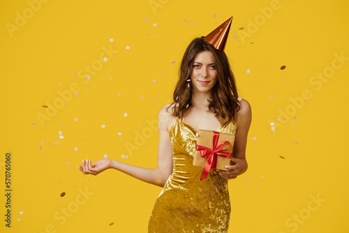 Obraz na plátně Happy lady holding wrapped gift boxes, wearing festive dress and birthday hat, y