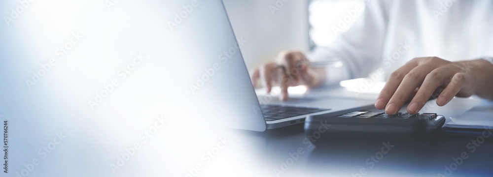 Close up hands of accountant using calculator to calculate tax refund. Business woman working on laptop and accounting financial report at office with copy space - obrazy, fototapety, plakaty 