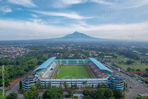 Sleman Yogyakarta, April 6, 2022 : View of Maguwoharjo Stadium from the air on a sunny morning. view of the stadium against the backdrop of the majestic Mount Merapi.  photo
