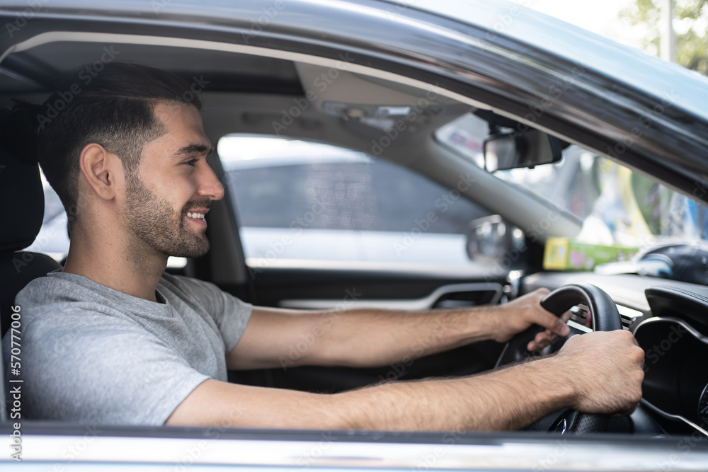 Happy man driving a car and smiling. Cute young Hispanic male success happy brunette. Portrait of happy driver steering car Holiday.