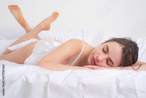 Beautiful young woman sleeping on bed at home. Sleeping girl. Sleeping woman resting in sleeping bed. Tender woman lying in bed and keeping eyes closed.