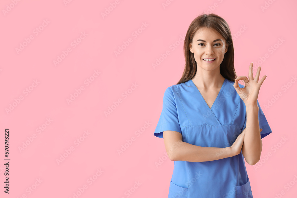 Female medical intern showing OK on pink background Female medical intern showing OK on pink background