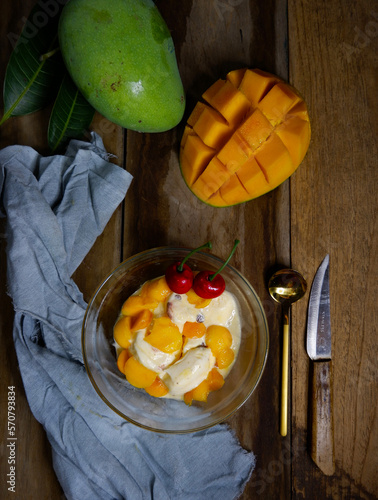 Fresh mango - beautiful diced fresh mango on dark wood background. Tropical fruit design concept. Served with vanila ice cream and cherry, sweet and Juicy.