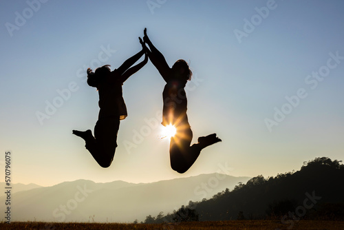 happy couple jumping on mountain meadow sunset background